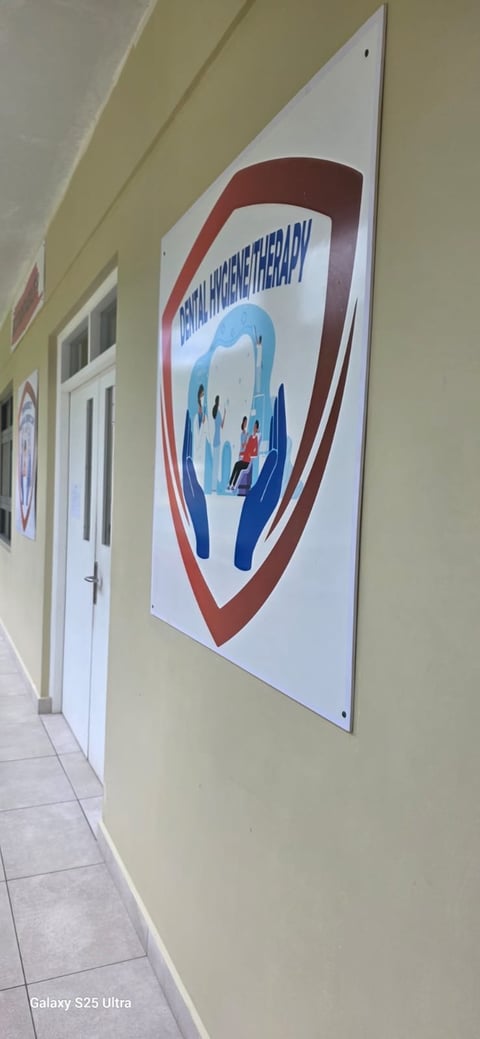 Sign mounted on pale yellow wall in a hallway featuring red and blue logo with text and silhouettes of people