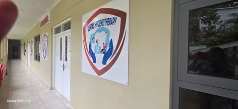 A hallway with pale yellow walls displaying a red and blue shield logo on white signage, with white doors and windows lining the corridor